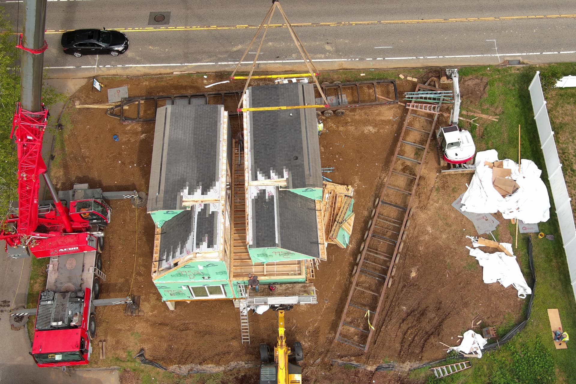 Aerial view of a crane setting Simplex modular home modules onto a foundation in Connecticut